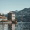 Scenic view of villas by Lake Como surrounded by lush mountains under a clear blue sky.