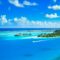 Aerial view of a luxurious tropical resort on a pristine island surrounded by azure waters and lush greenery.